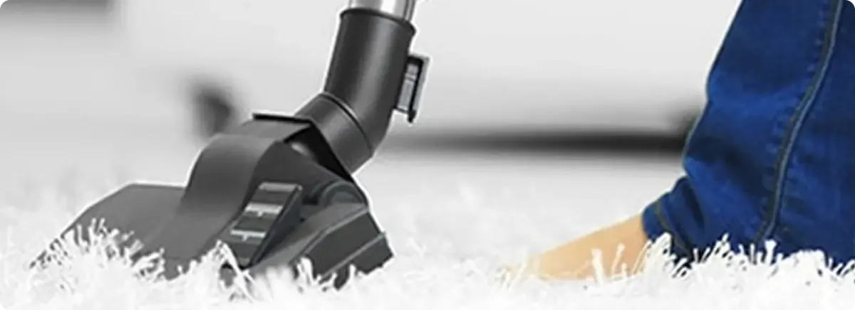 Close-up of a professional vacuuming a white carpet in Sandia Park.